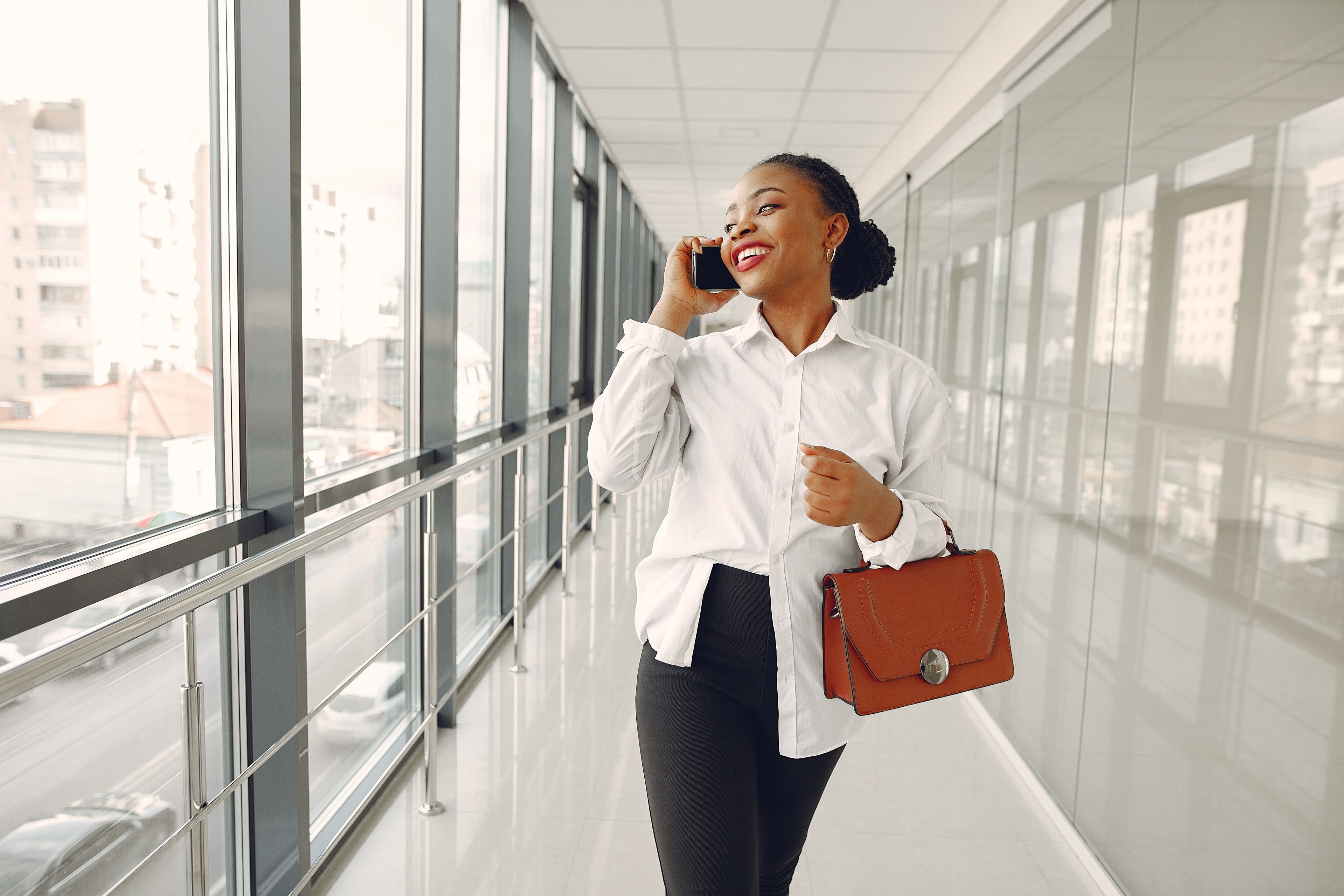 A smiling professional using her phone in a bright city office