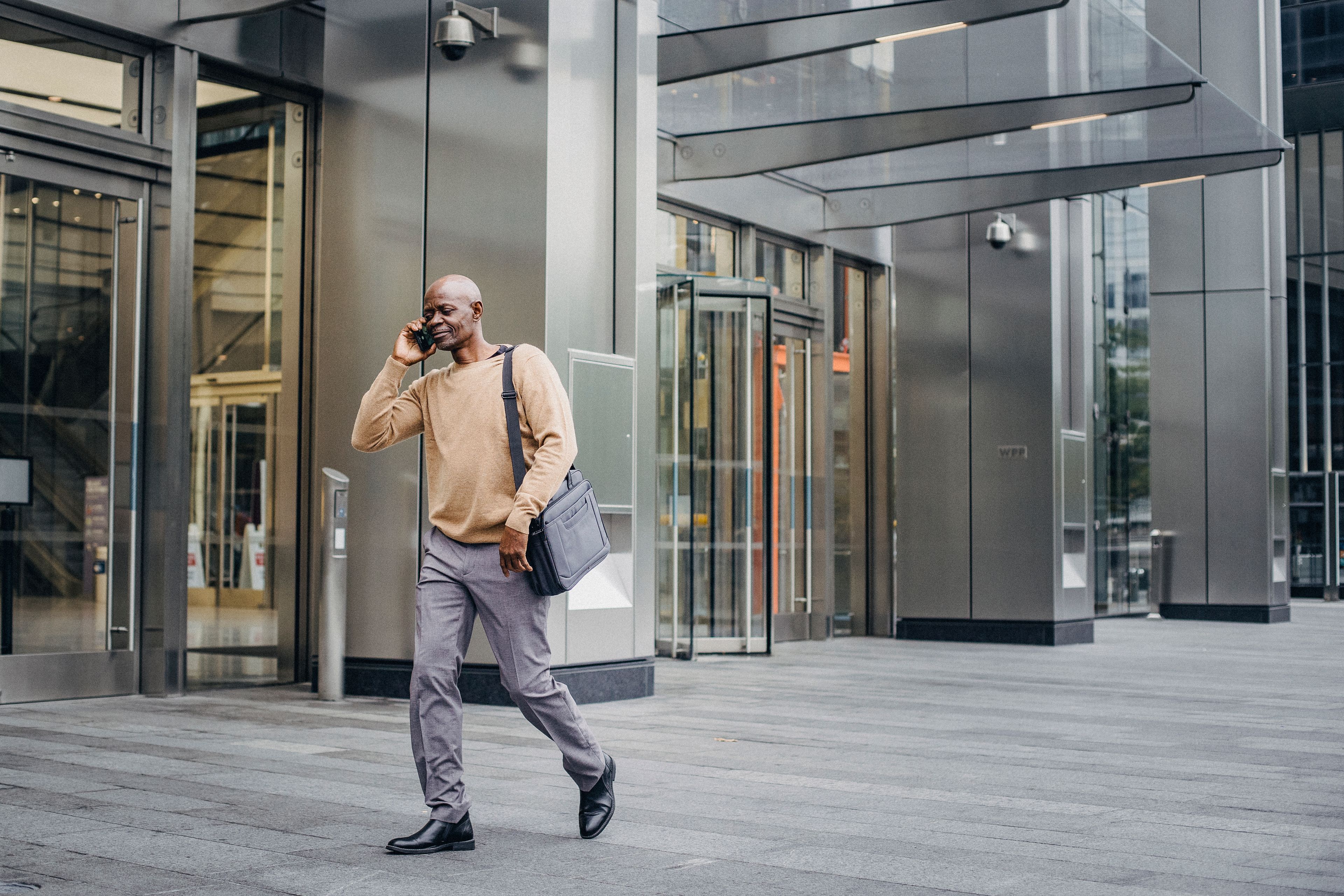 A professional walking through the city while speaking on his phone